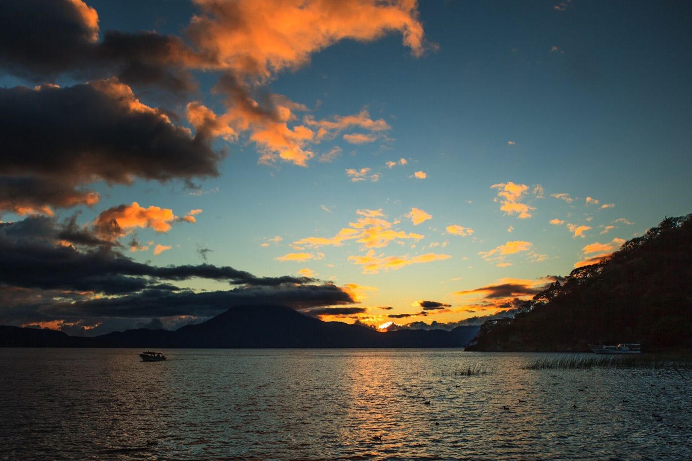 Atardecer sobre el Lago de Atitlán con nubes anaranjadas