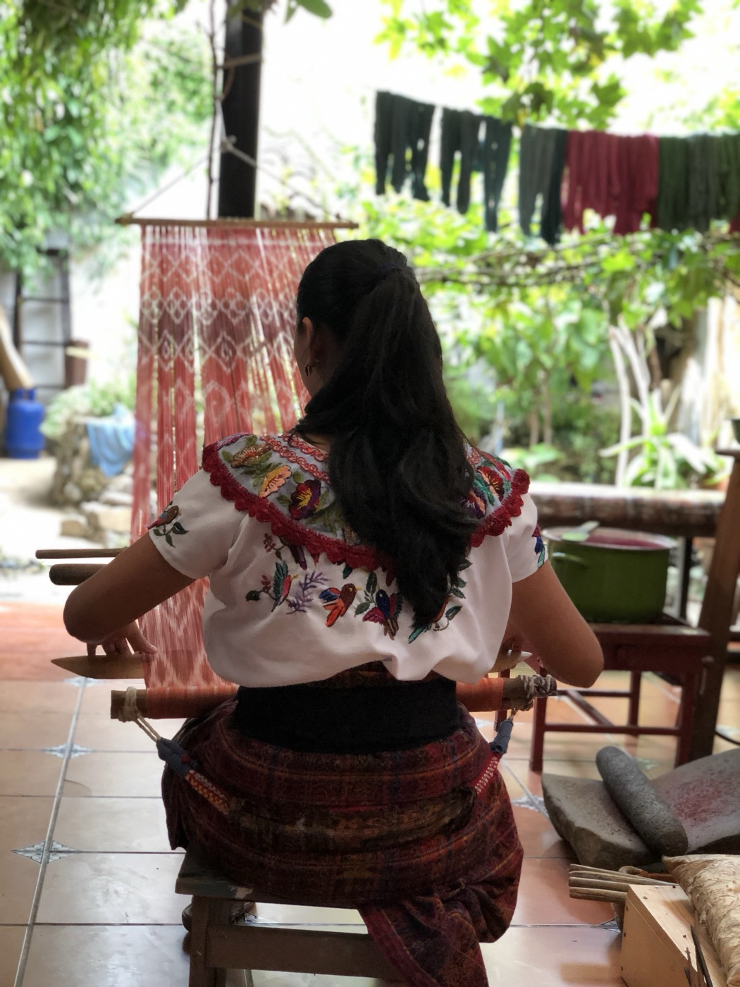 Mujer tejiendo en telar de cintura al estilo maya